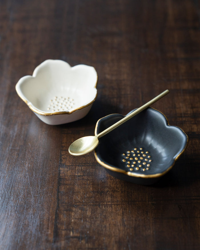 Pair of Lotus Trinket Trays in white and black with gold rims and a spoon.