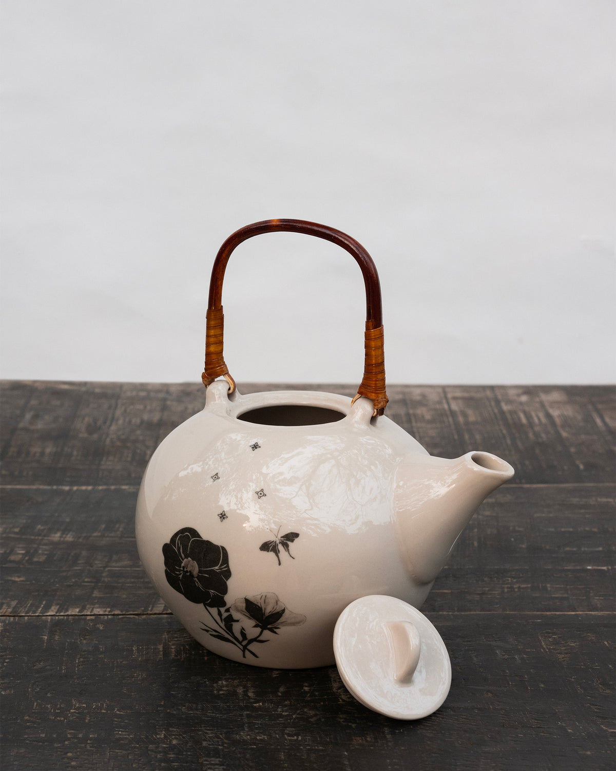 Poppy teapot with lid removed beside it on a dark wooden table.