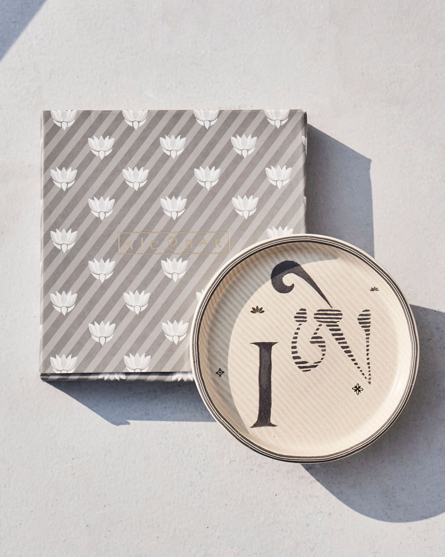 The Akshar Coaster beside its striped gift box.