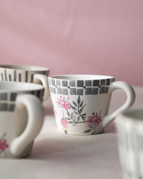 Close view of a mug with a checked rim and pink blossom