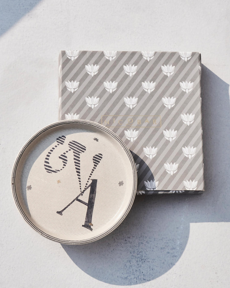 The Akshar Coaster beside its striped gift box.