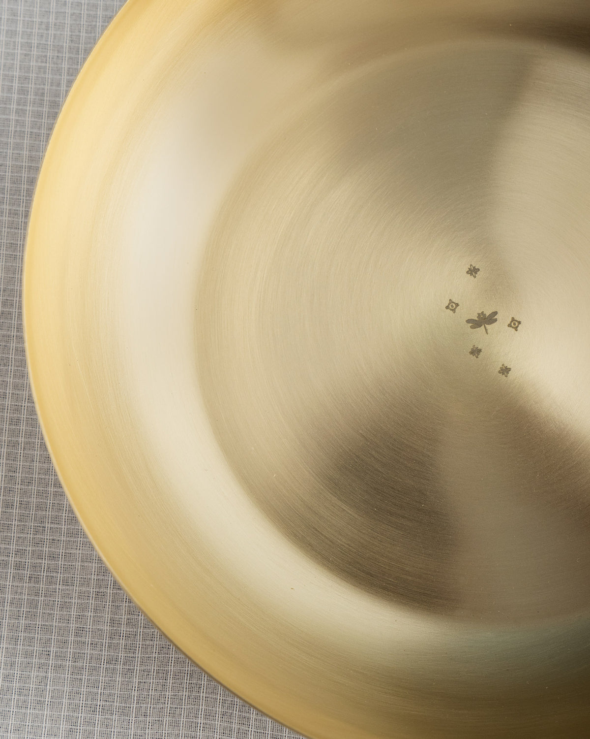 Close-up of a brass Madhu shallow bowl showing a dragonfly mark.
