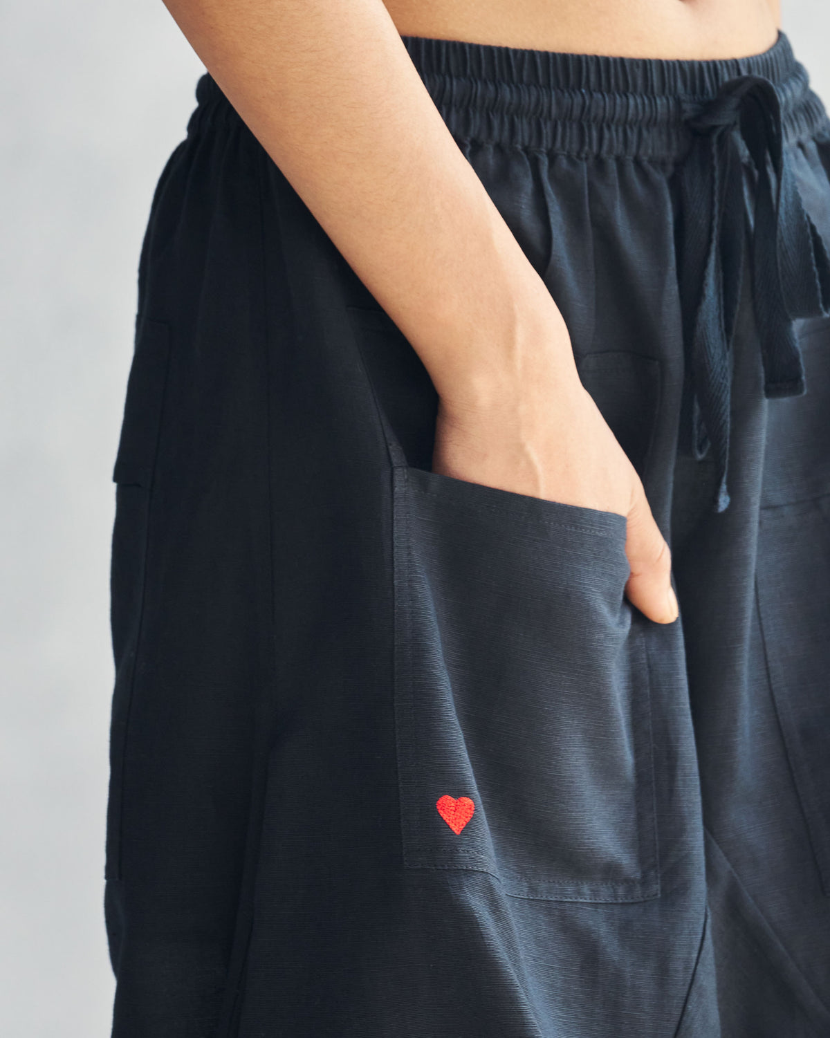 Close-up of Yoka trousers showing the red heart embroidery on the pocket.