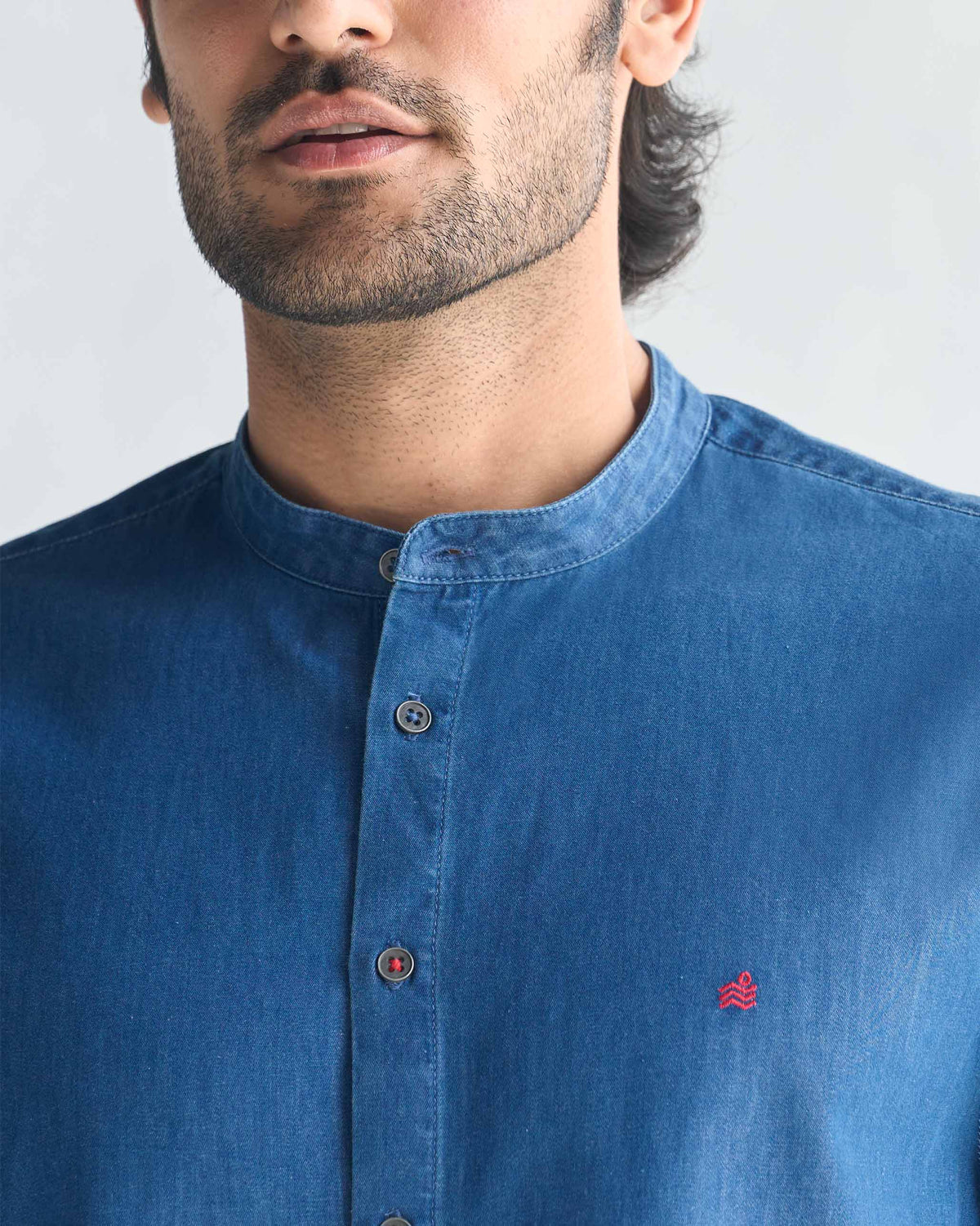 Close-up of a blue Nawab Shirt showing the band collar and red chest embroidery.
