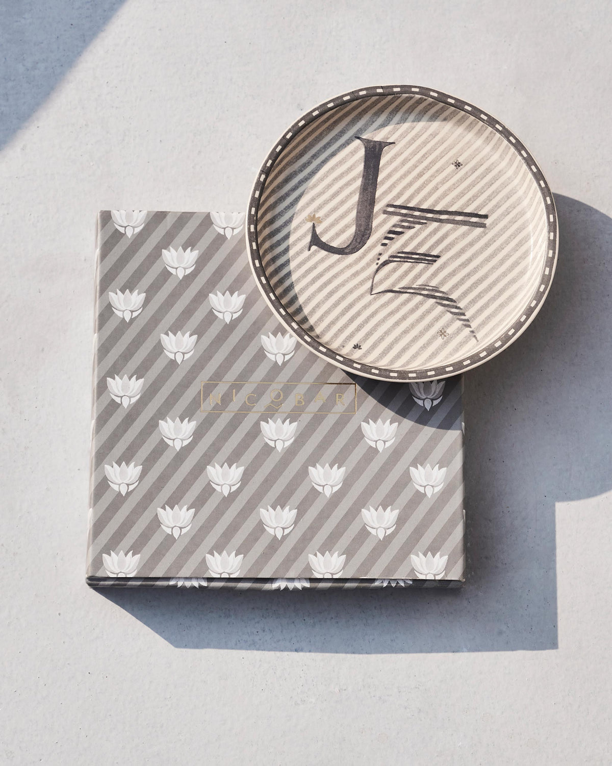 Akshar Coaster with a letter J set on its lotus-print gift box.