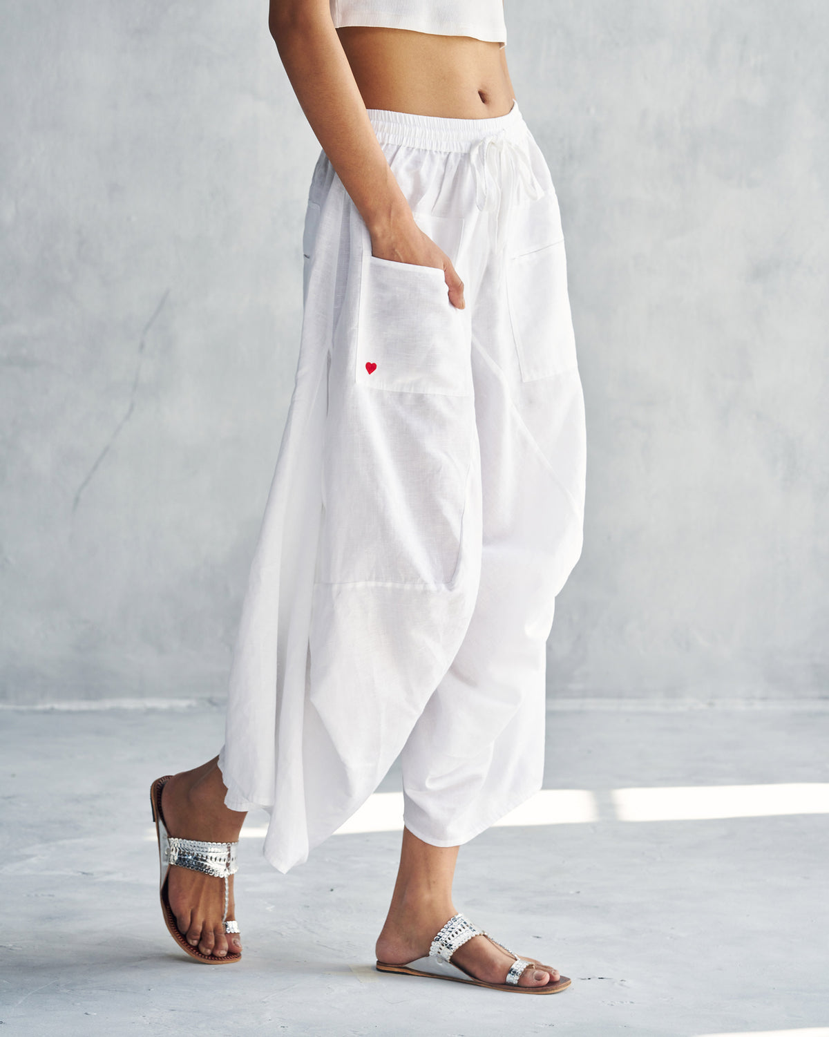 Side view of white Yoka Trousers showing a small red heart on the pocket.