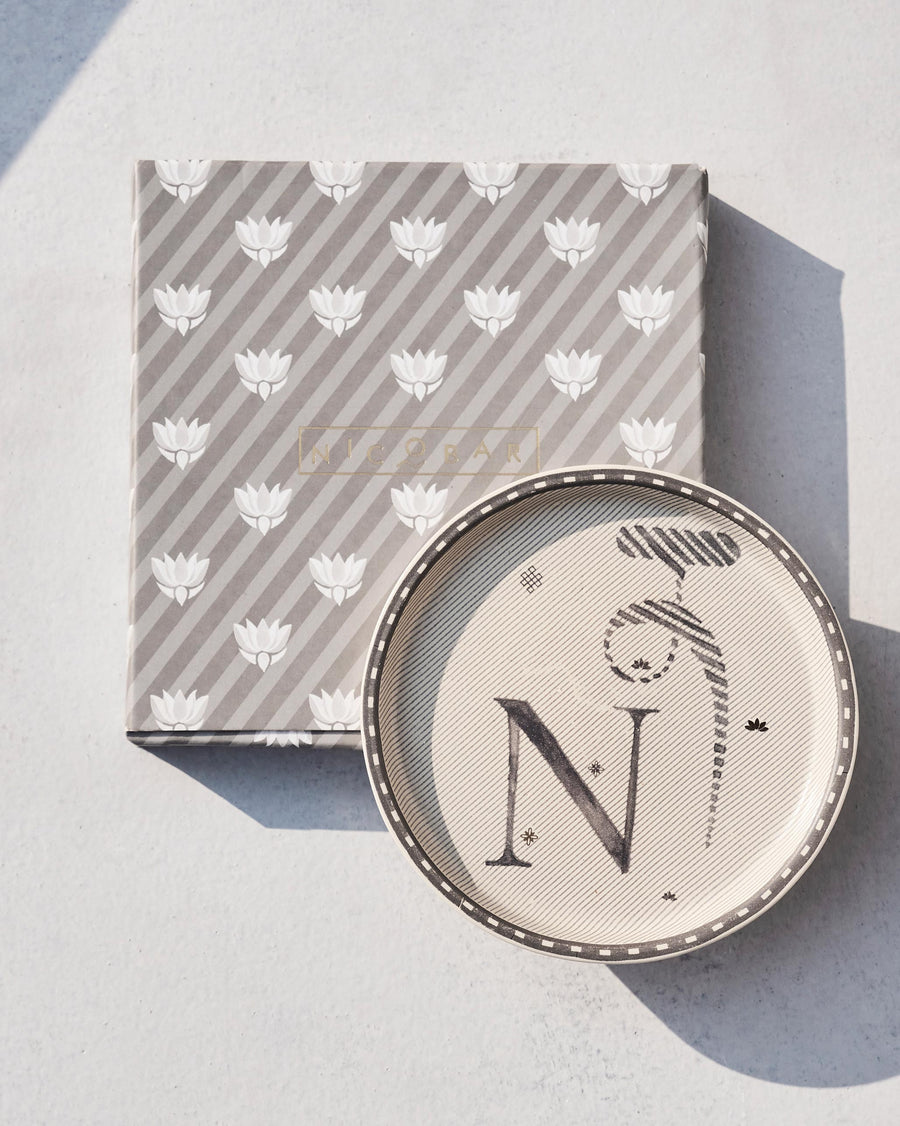 The Akshar Coaster beside its striped gift box.