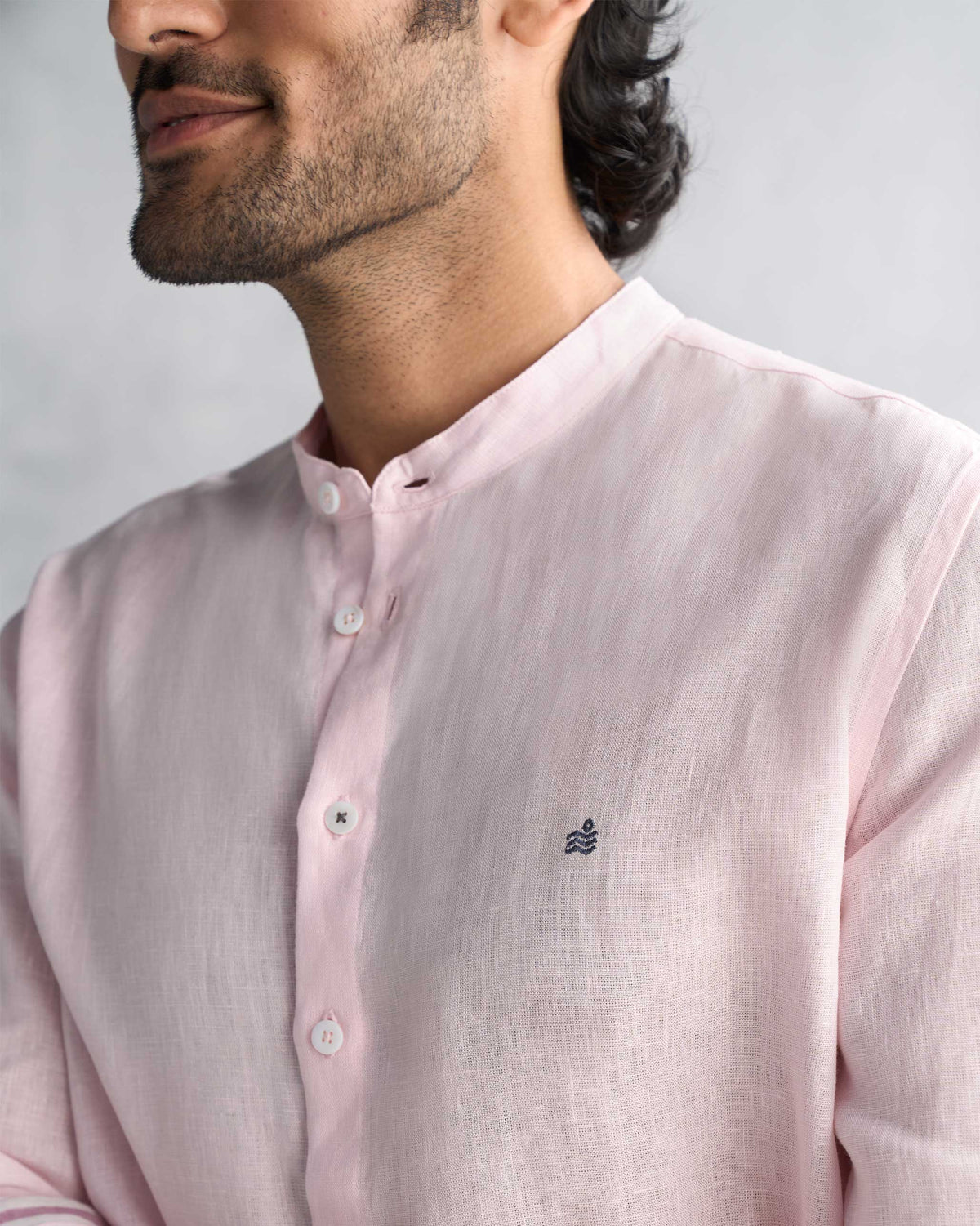Close-up of a pink Nawab Shirt showing the band collar and navy chest embroidery.