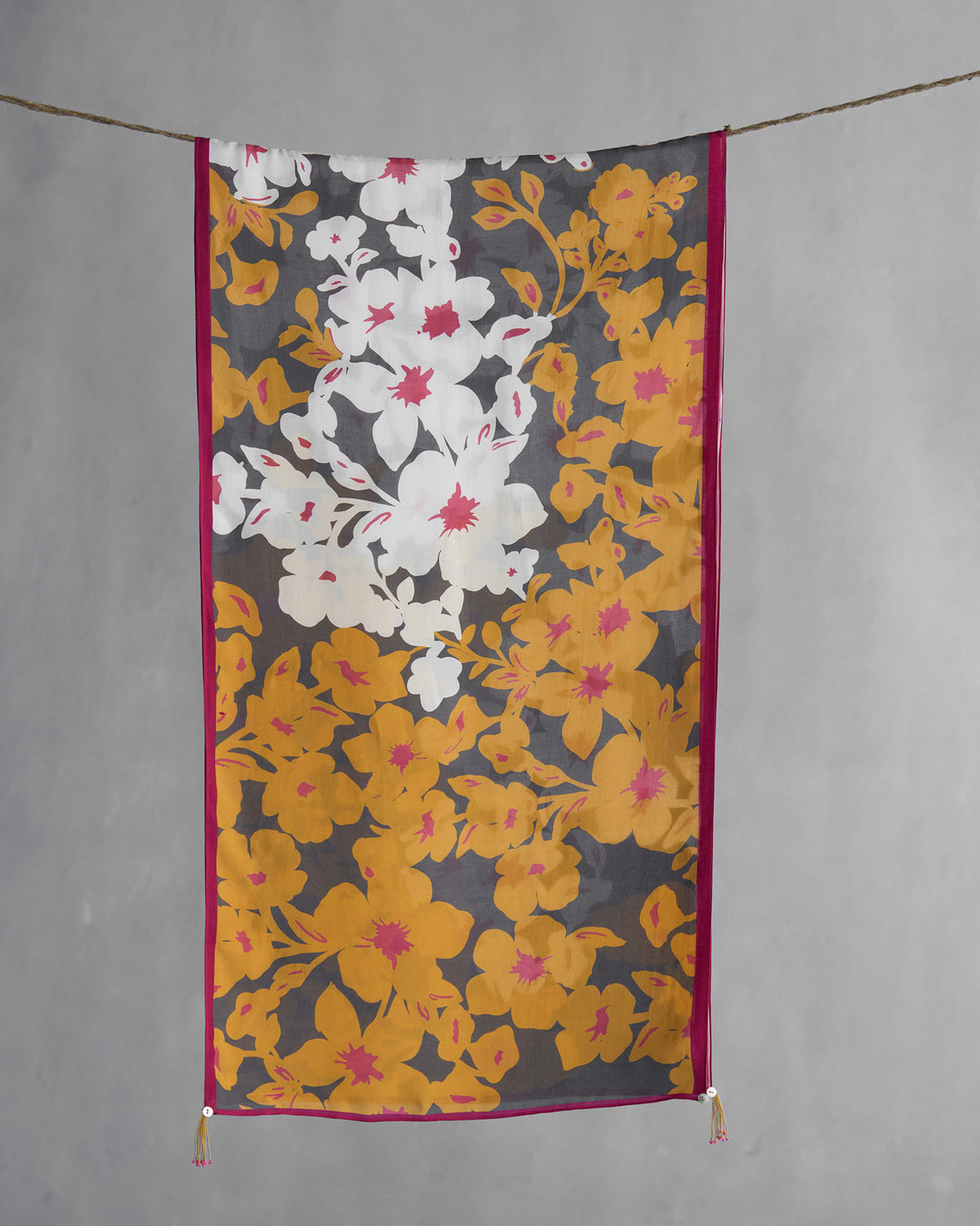 Gudhal scarf hung flat, showing white and ochre flowers on grey with pink edging.