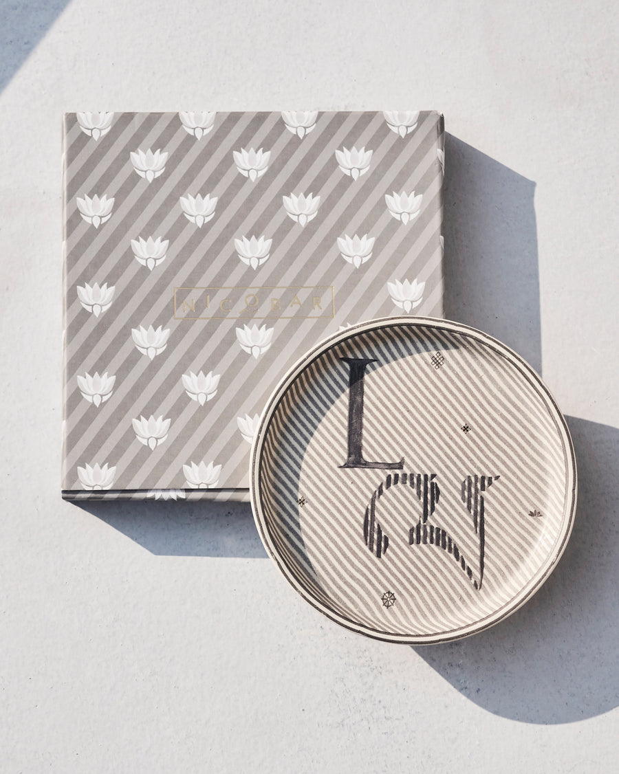 The Akshar Coaster beside its striped gift box.