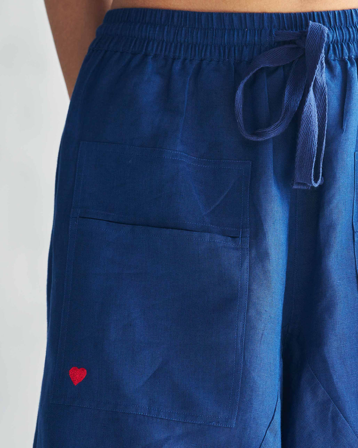 Close-up of a red heart on the pocket of navy Yoka Trousers.