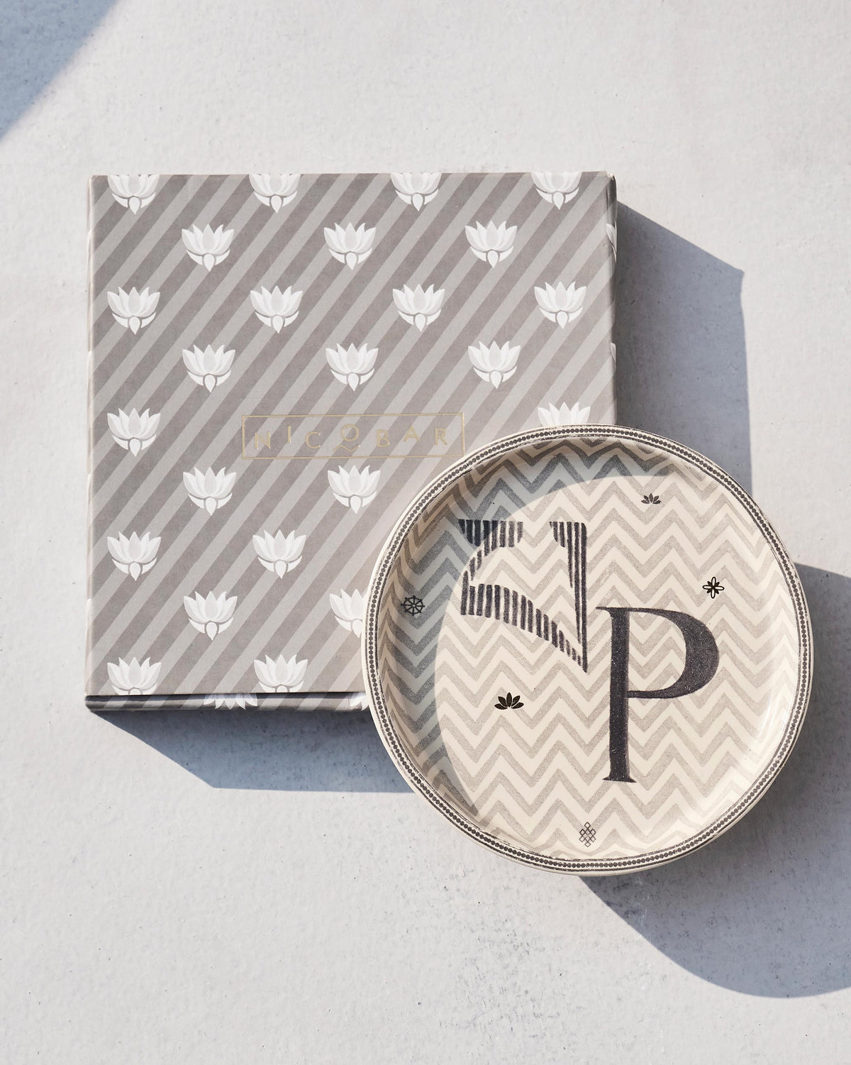 Akshar Coaster with a letter P set on its lotus-print gift box.