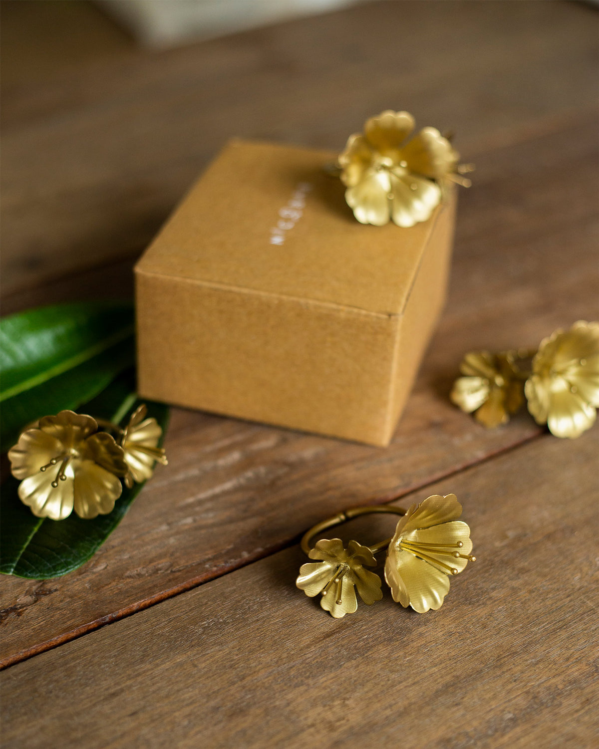 Kachnar Napkin Rings with gold flower motifs laid out on a wooden table.