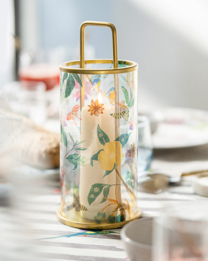 Wildflower lantern with a gold frame and floral print, with a pillar candle inside.