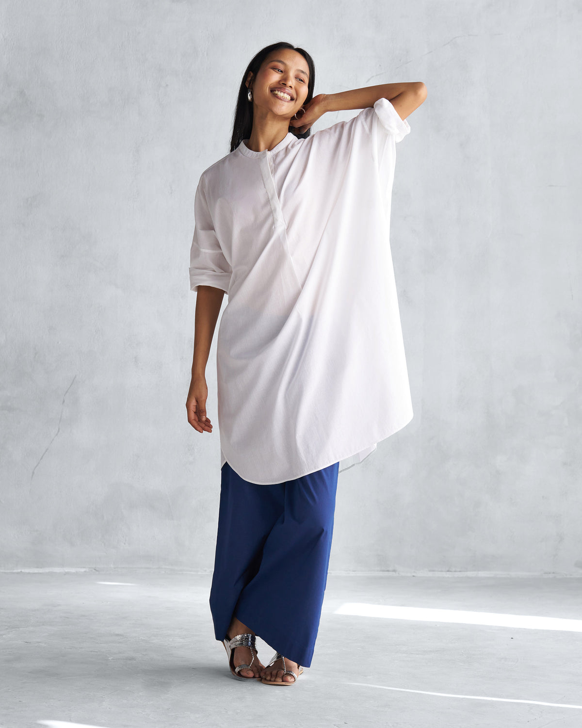 Person wearing a white Lazy Sunday tunic with a curved hem.