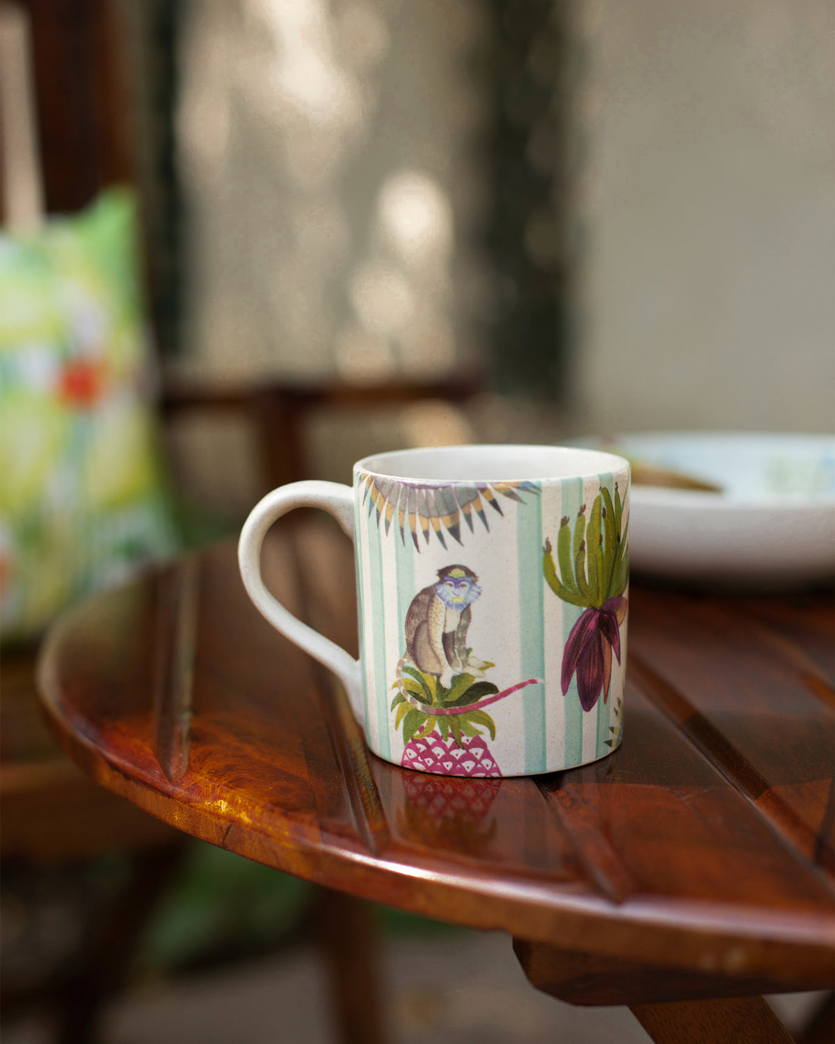 Ivory Mahi Mug with a monkey and leaf print on a wooden table.