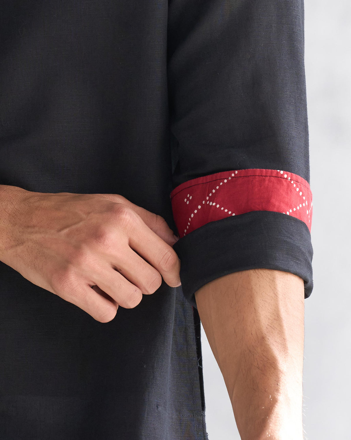 Close-up of a black Chandni Chowk kurta sleeve with red patterned lining.