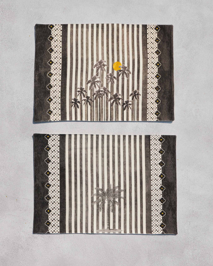 Pair of Midnight placemats with palm trees and stripes laid flat.