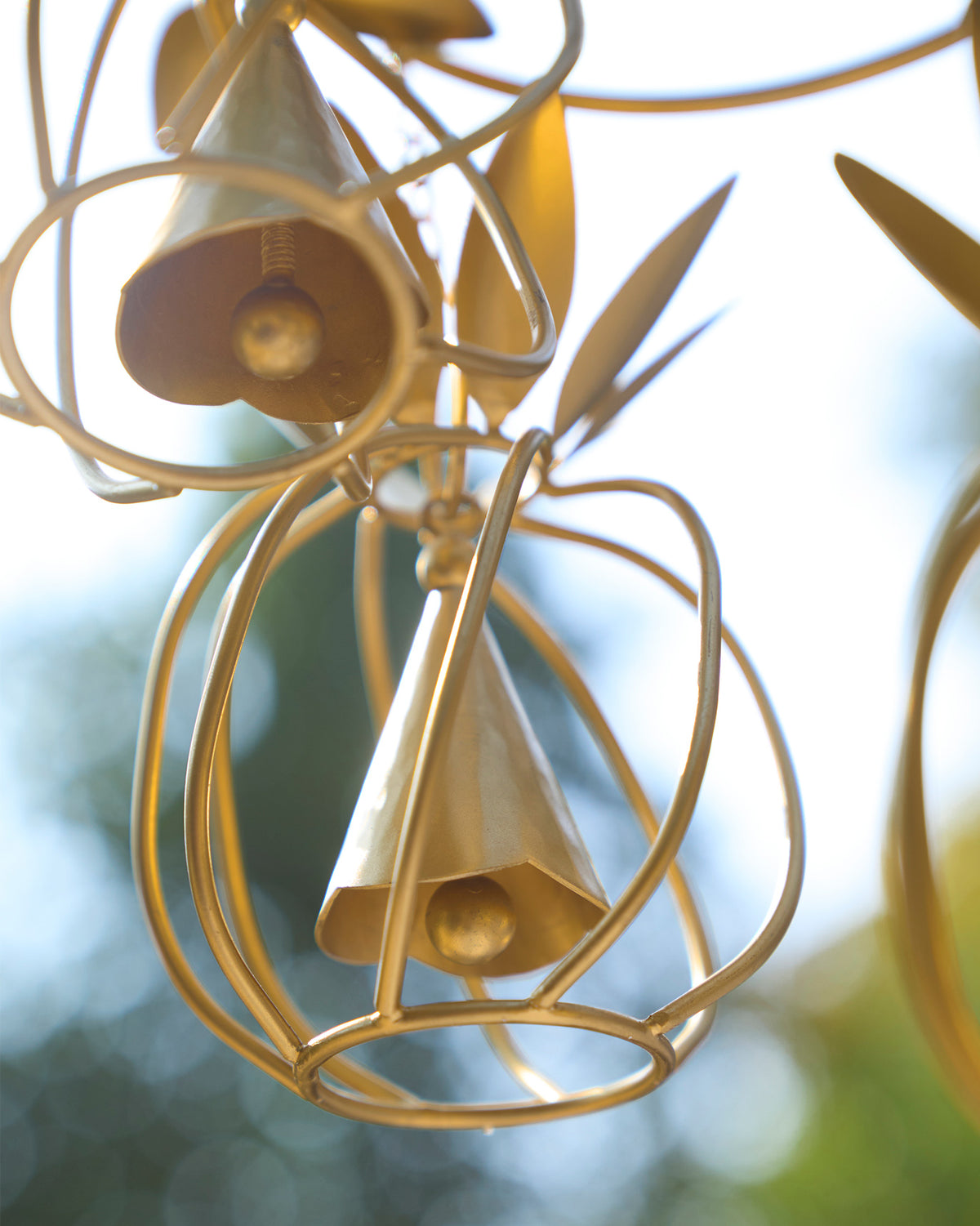 Close-up of gold pineapple wind chime bells in open wire cages.
