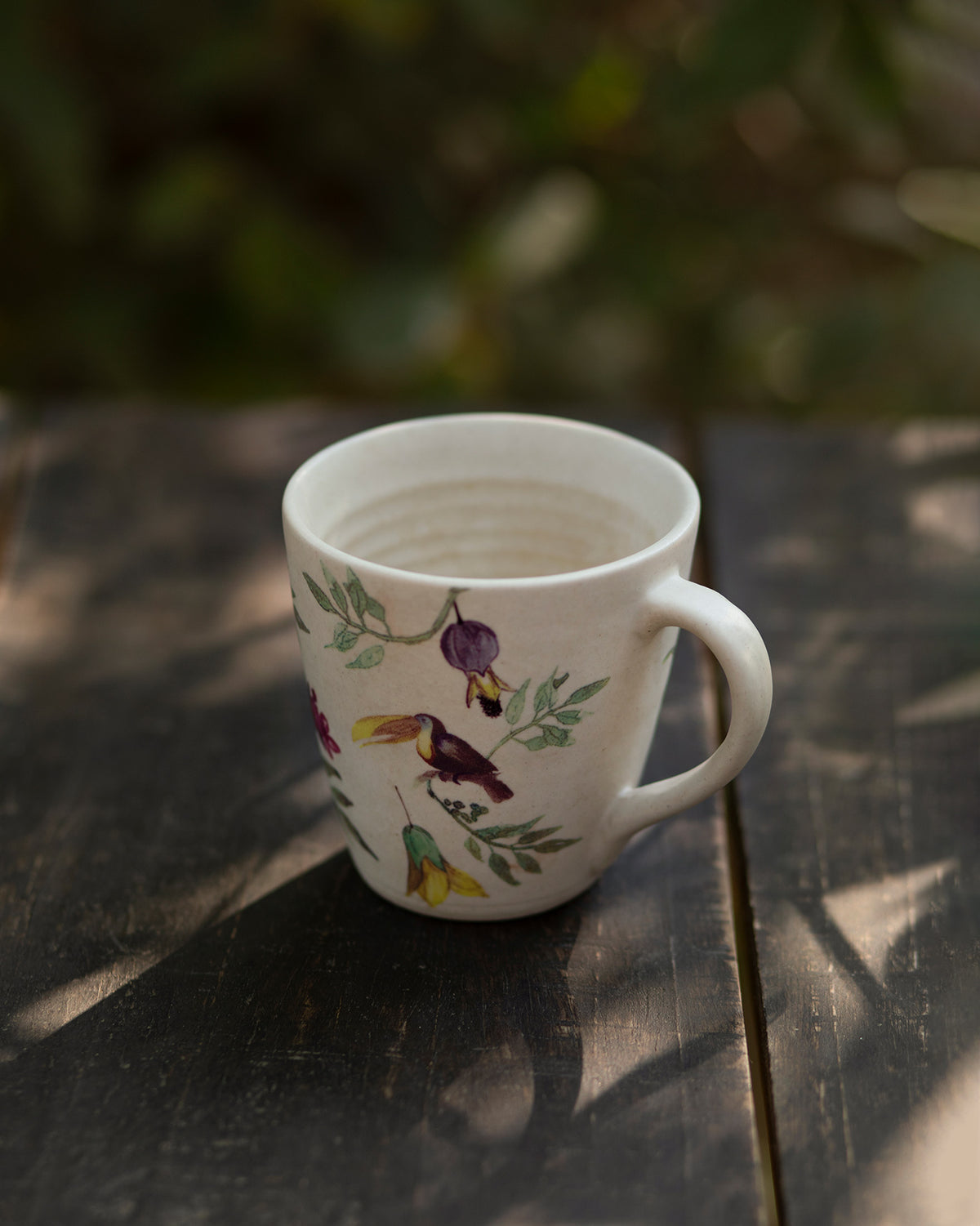 Nakano mug with birds and leafy branches printed around its side.