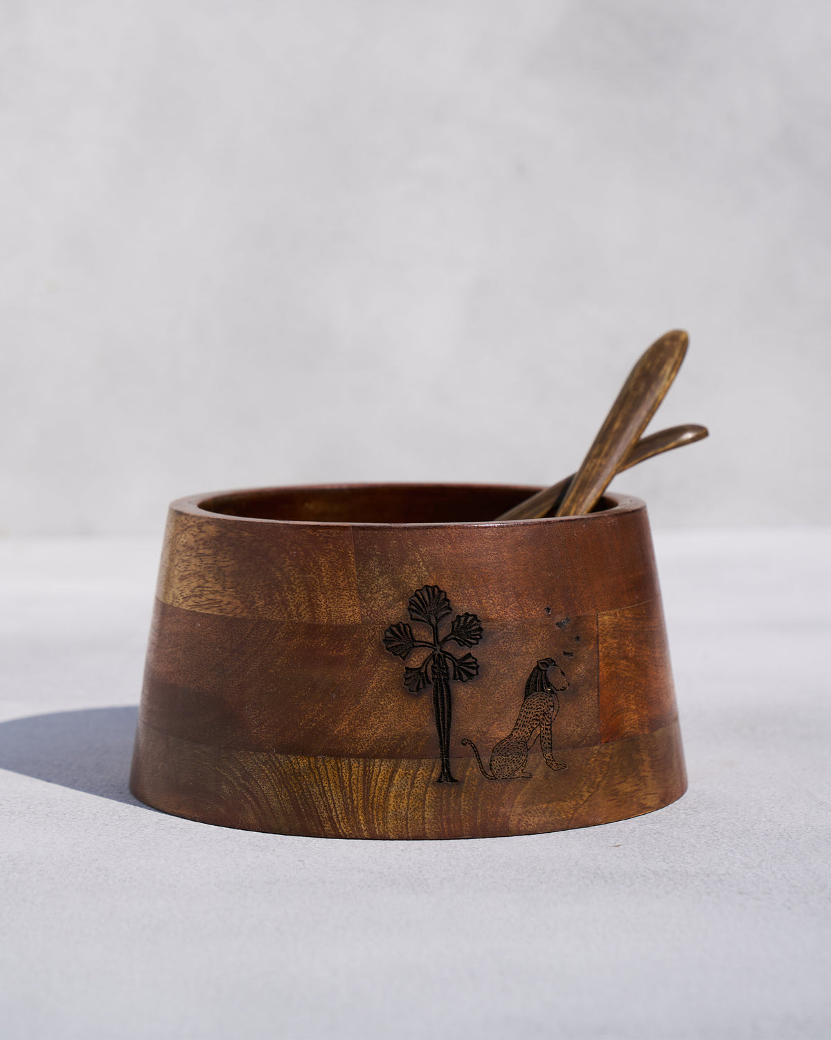 Bara mango wood salad bowl with palm engraving and wooden spoons inside.
