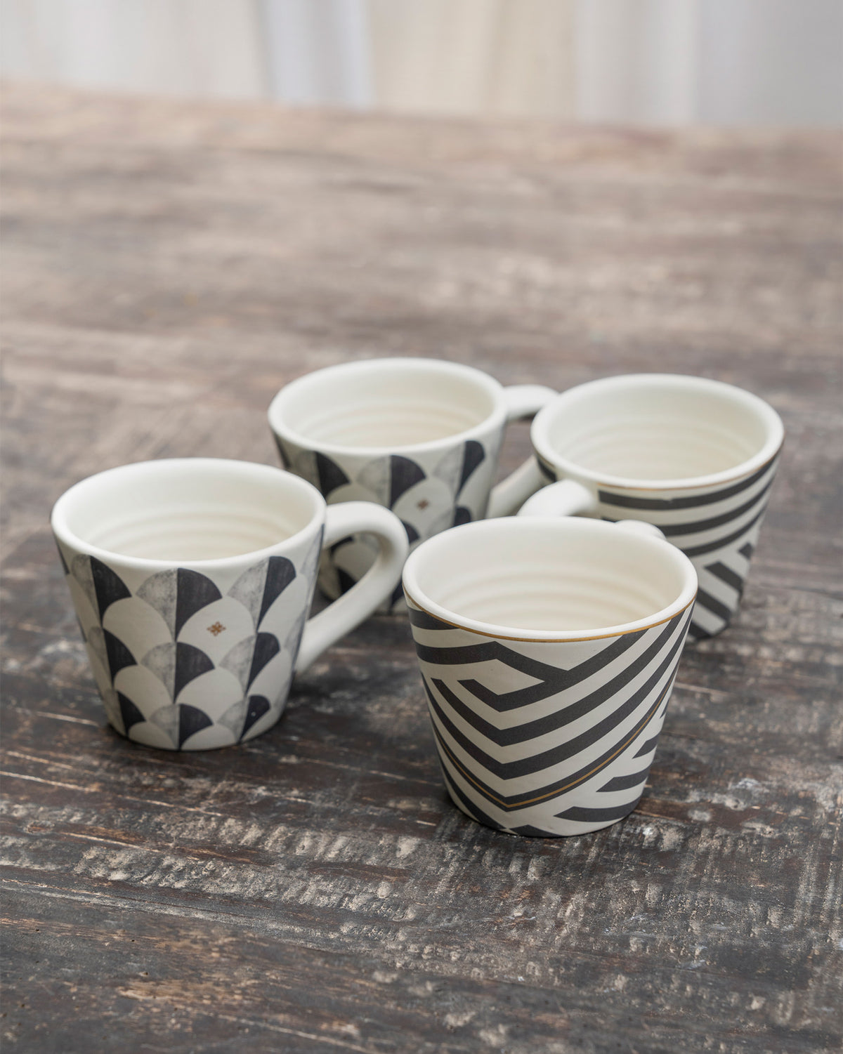 Four cream Khardung espresso mugs with charcoal scallop and stripe patterns.