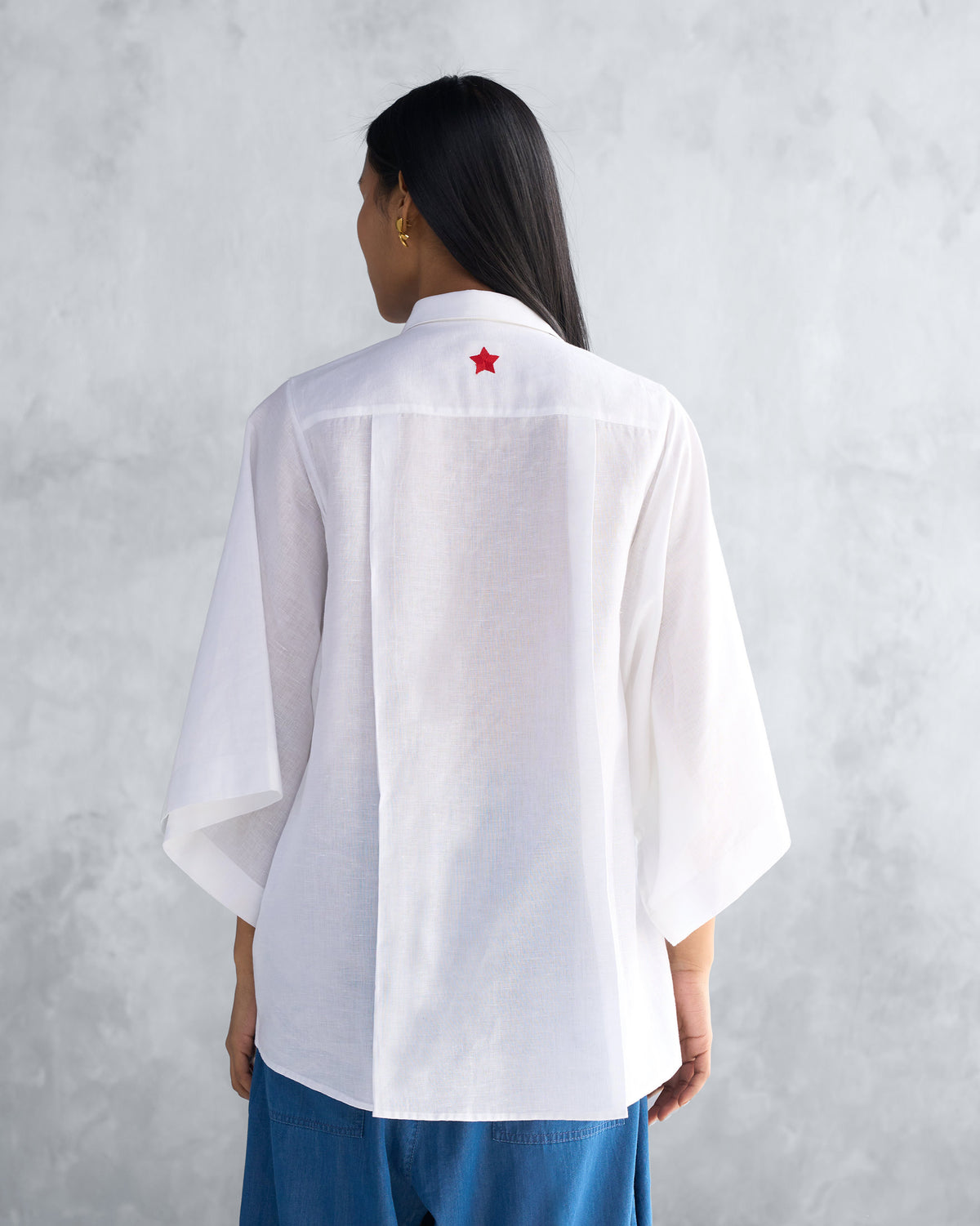 Back of a white Drop Armhole Shirt with a red star embroidery and box pleat.