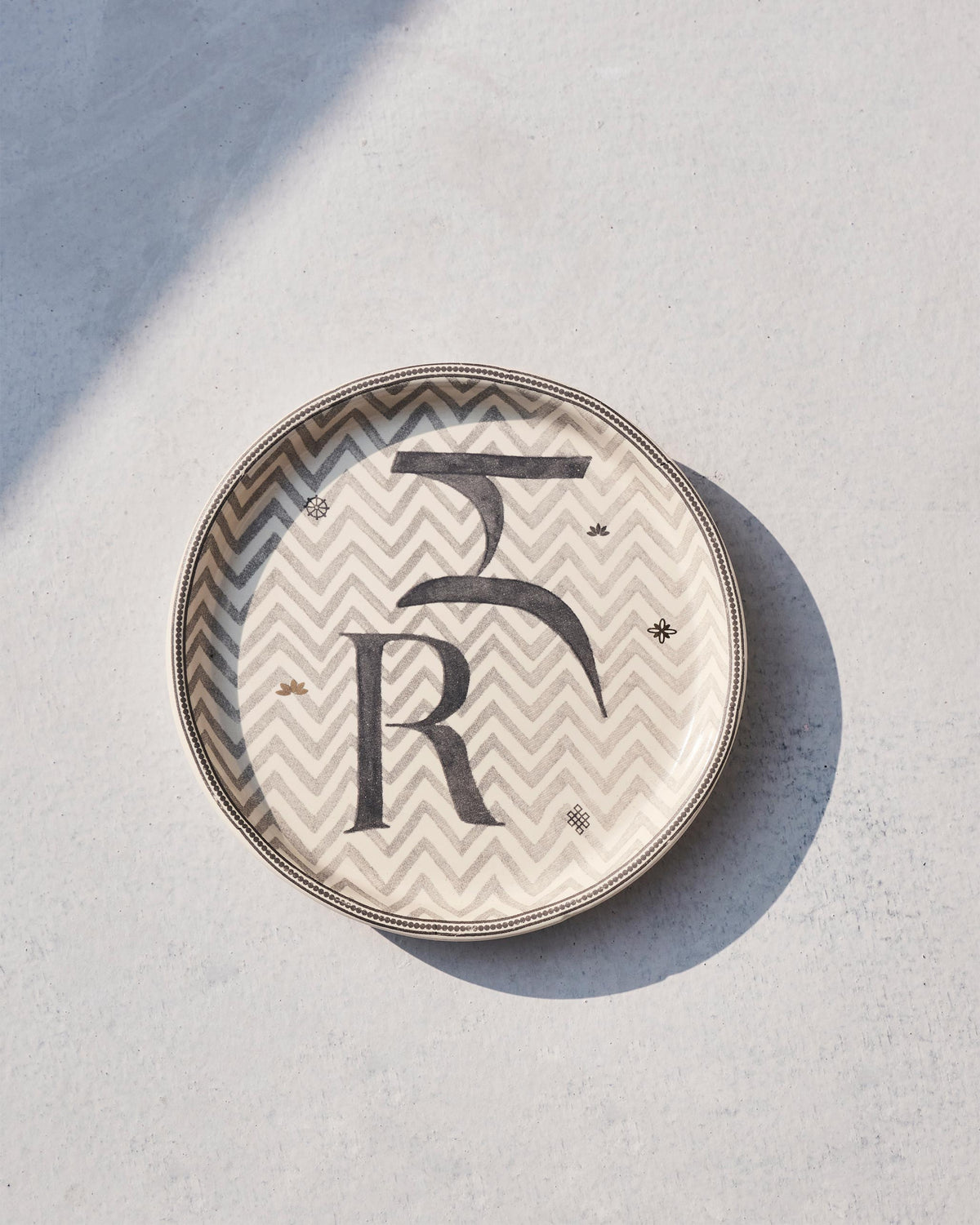 Akshar Coaster - R lying flat, showing its chevron pattern and beaded rim.