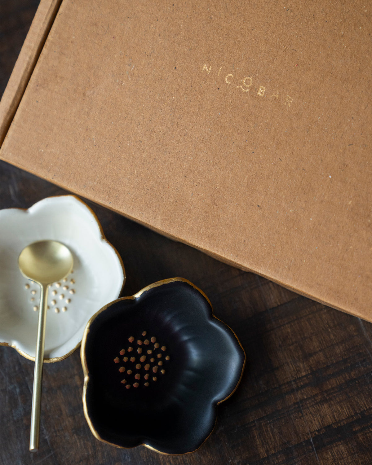 Lotus Trinket Trays in black and white with gold rims, shown with a gold spoon.