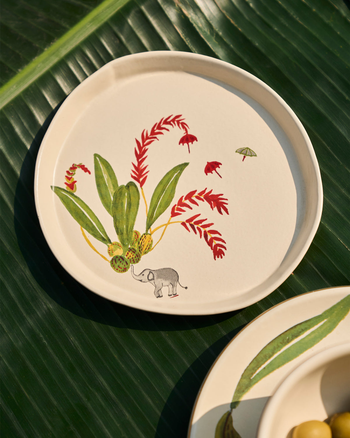 Thiri dessert plate with an elephant, leaves and small umbrella motifs.