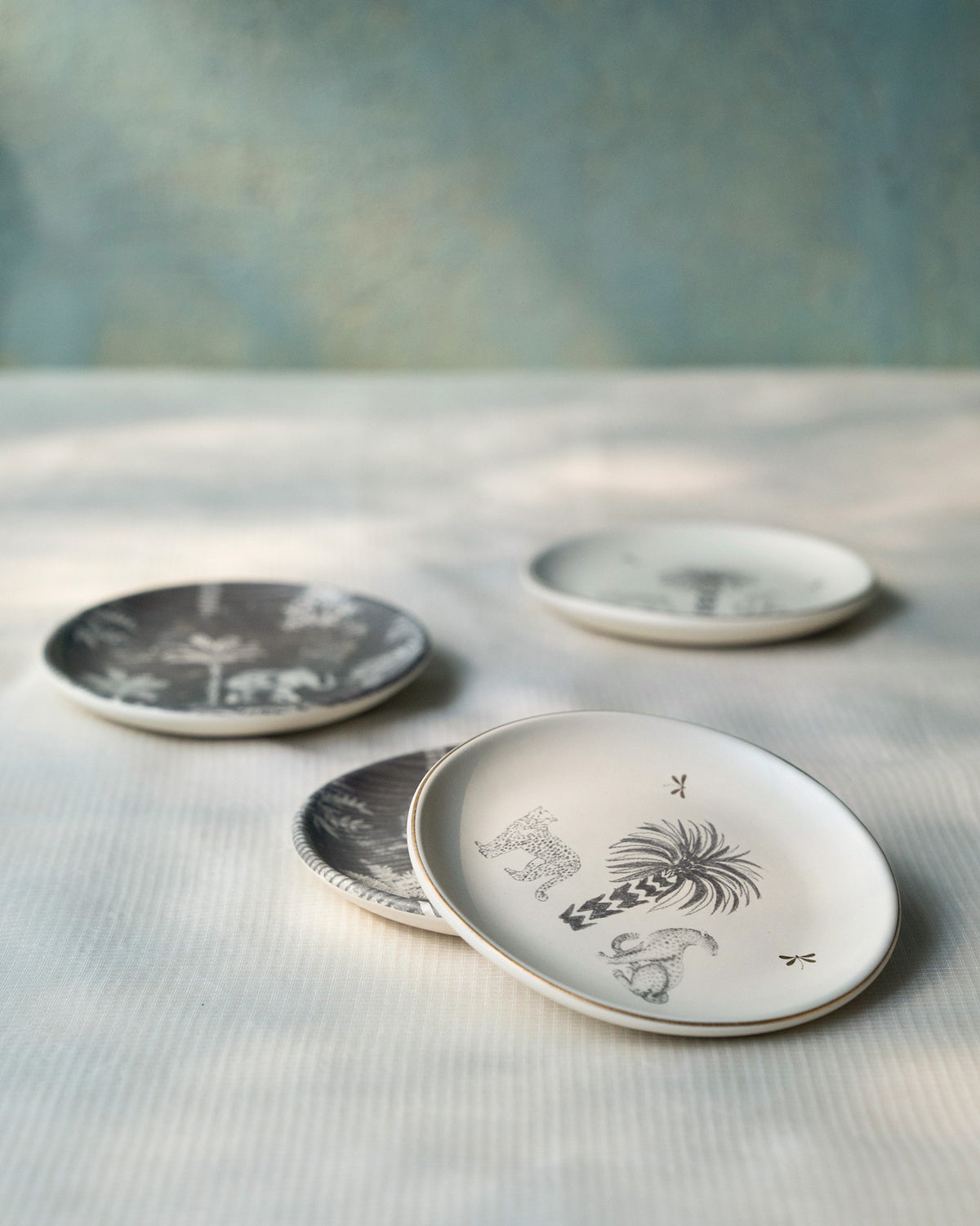 Periyar Tea Plates in grey and white with palm and animal designs.