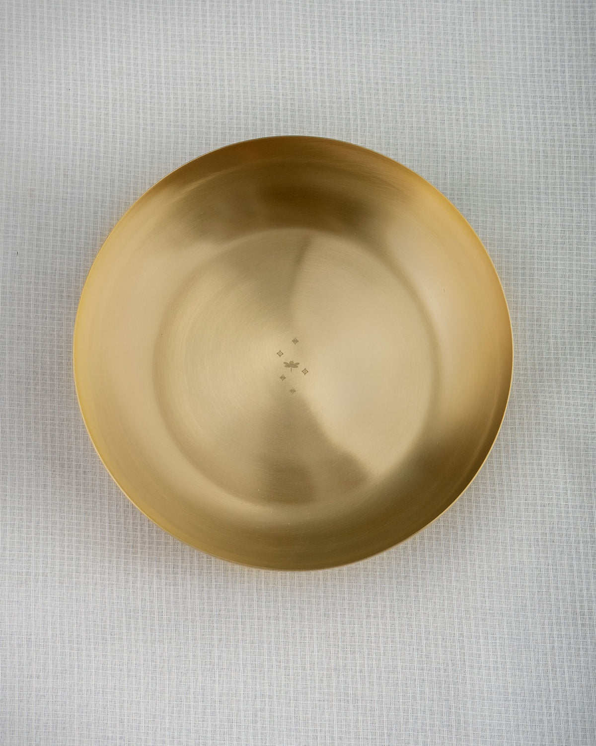 Overhead view of a brass Madhu shallow bowl with a dragonfly motif.