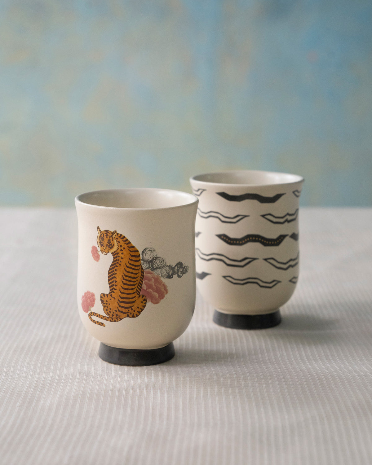Set of two Sitara tea cups, one with a tiger and one with black waves.