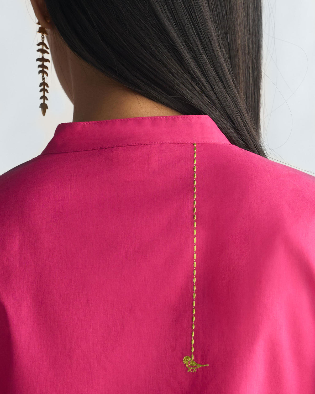 Close-up of the back of a berry long kurta with a lime-green bird motif.
