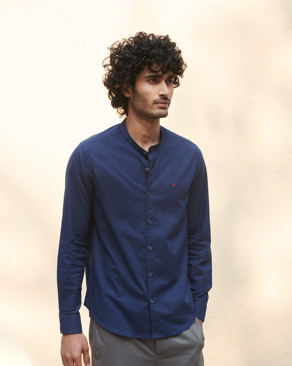 Person wearing a navy Nawab Shirt with a band collar and red chest mark.