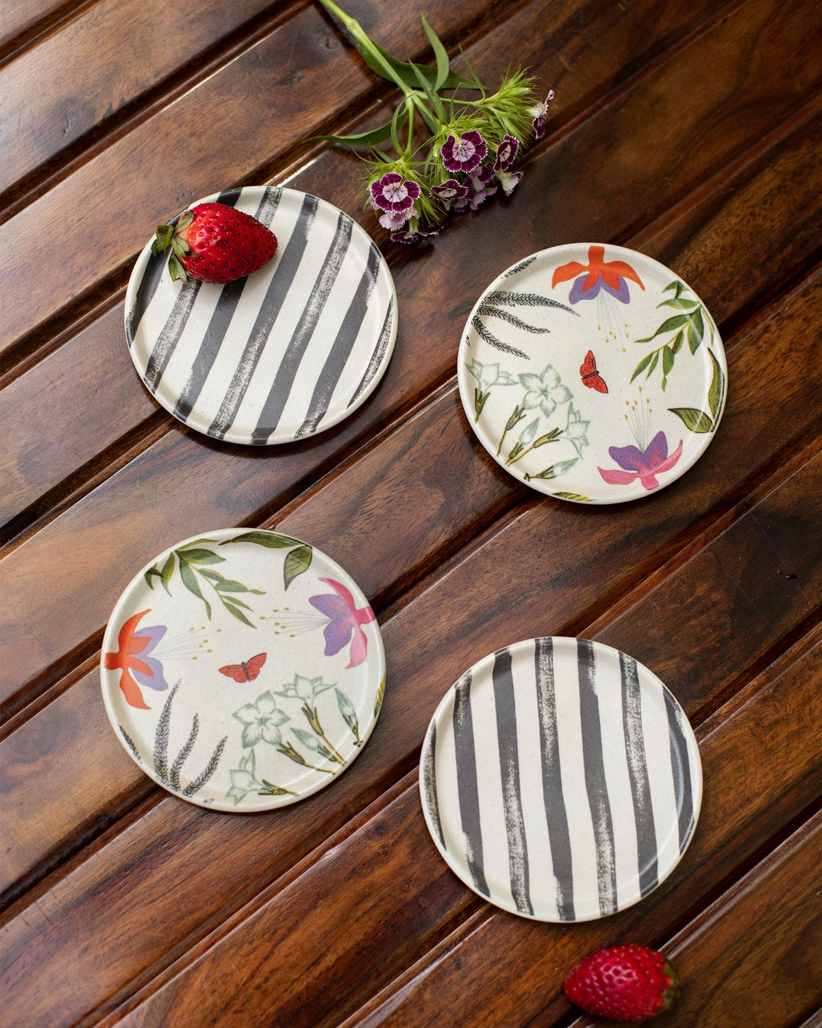 Set of four botanical coasters alternating black stripes and floral butterfly prints.