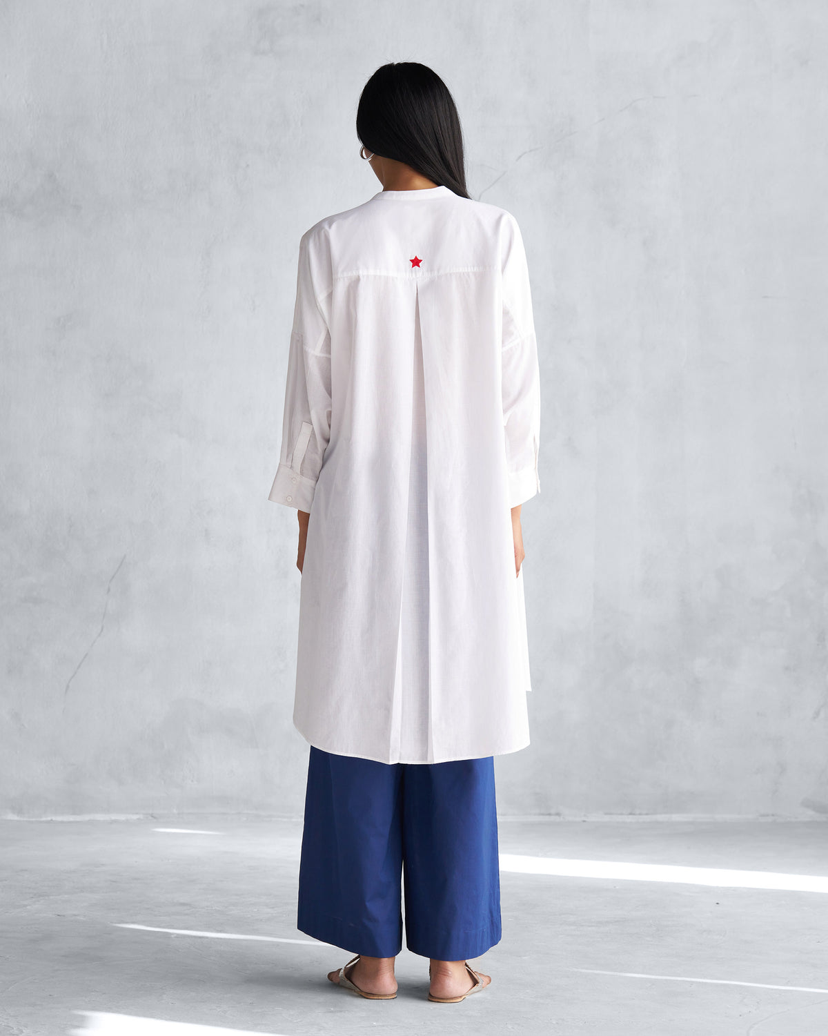 Back of a white Lazy Sunday tunic with a box pleat and red star.