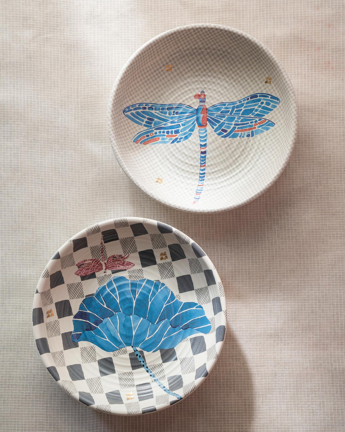 Two Nectar shallow bowls showing blue dragonfly and lotus leaf prints on checkered grounds.