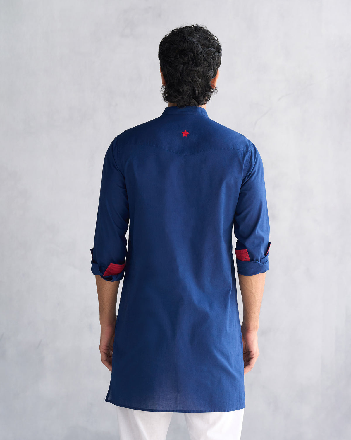 Back of a navy Pondicherry kurta with a red star and red-lined sleeves.