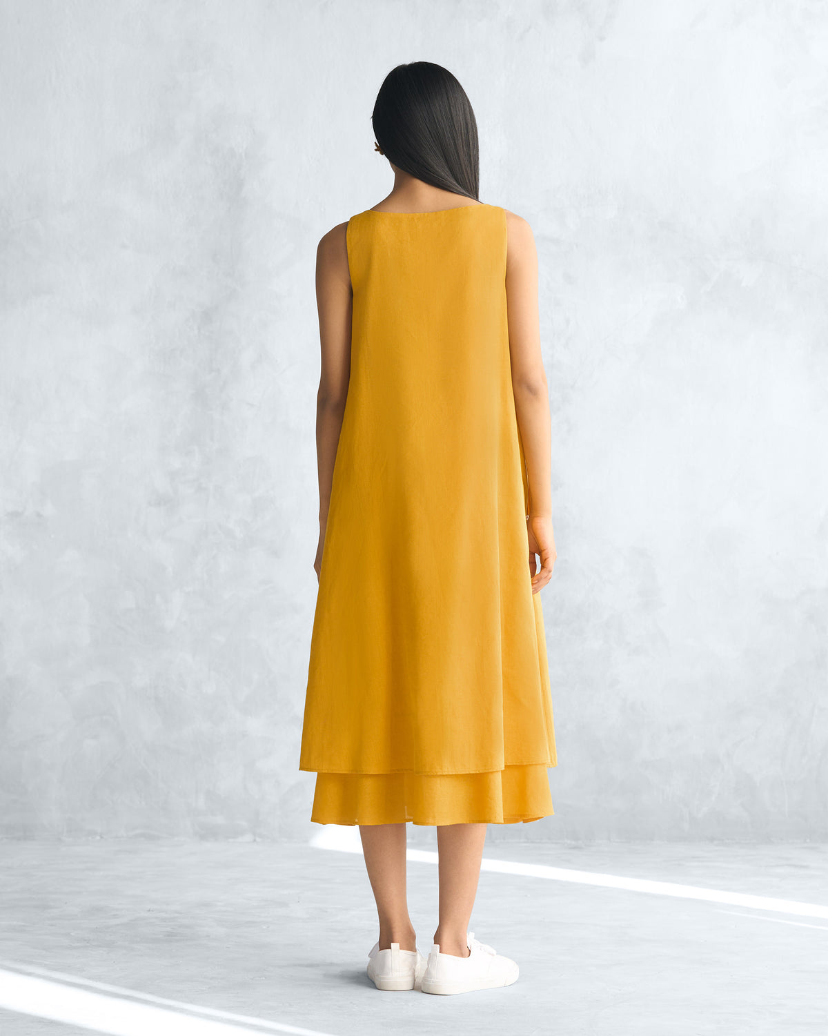 Back of a mustard yellow Double layer dress worn by a person.