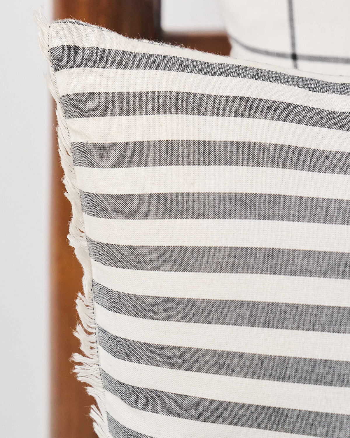 Close-up of Black & White cushion cover showing black stripes and a fringed edge.