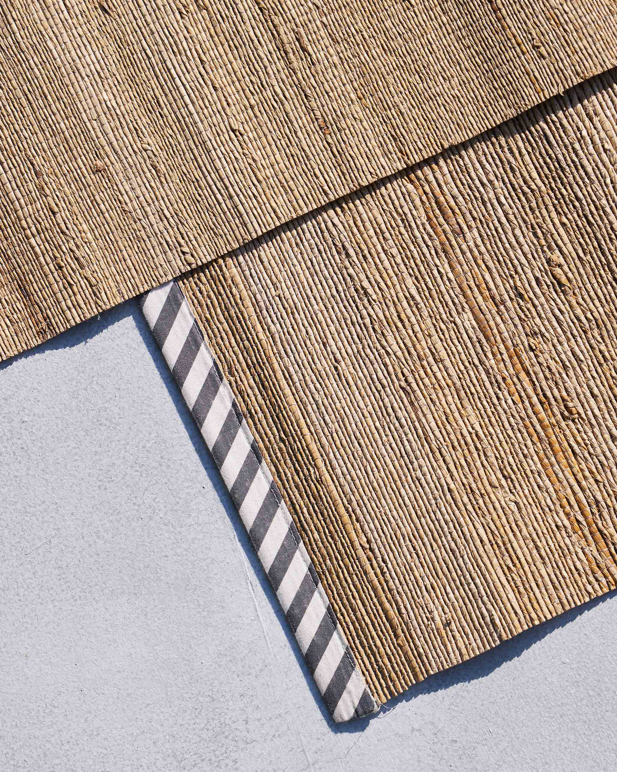 Close-up of woven banana fibre placemats with a black and white striped border.