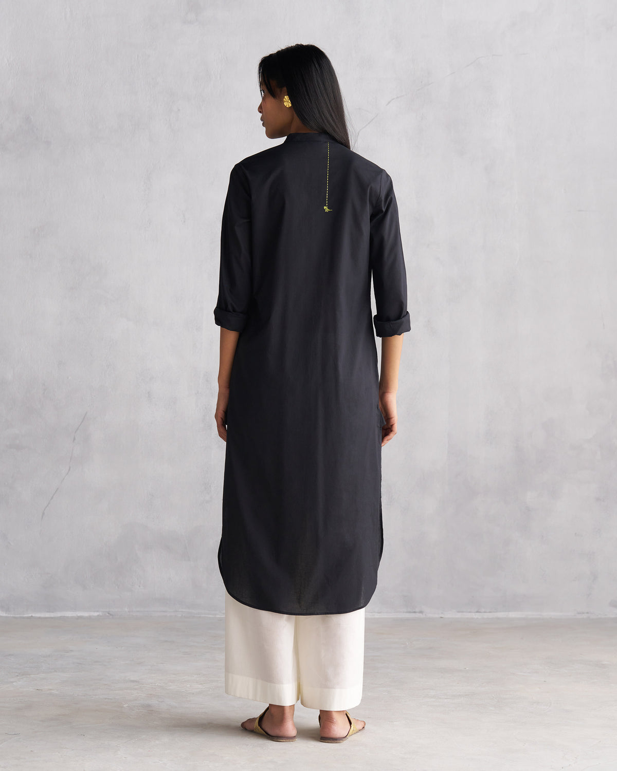 Back of a black long kurta with embroidered bird detail.