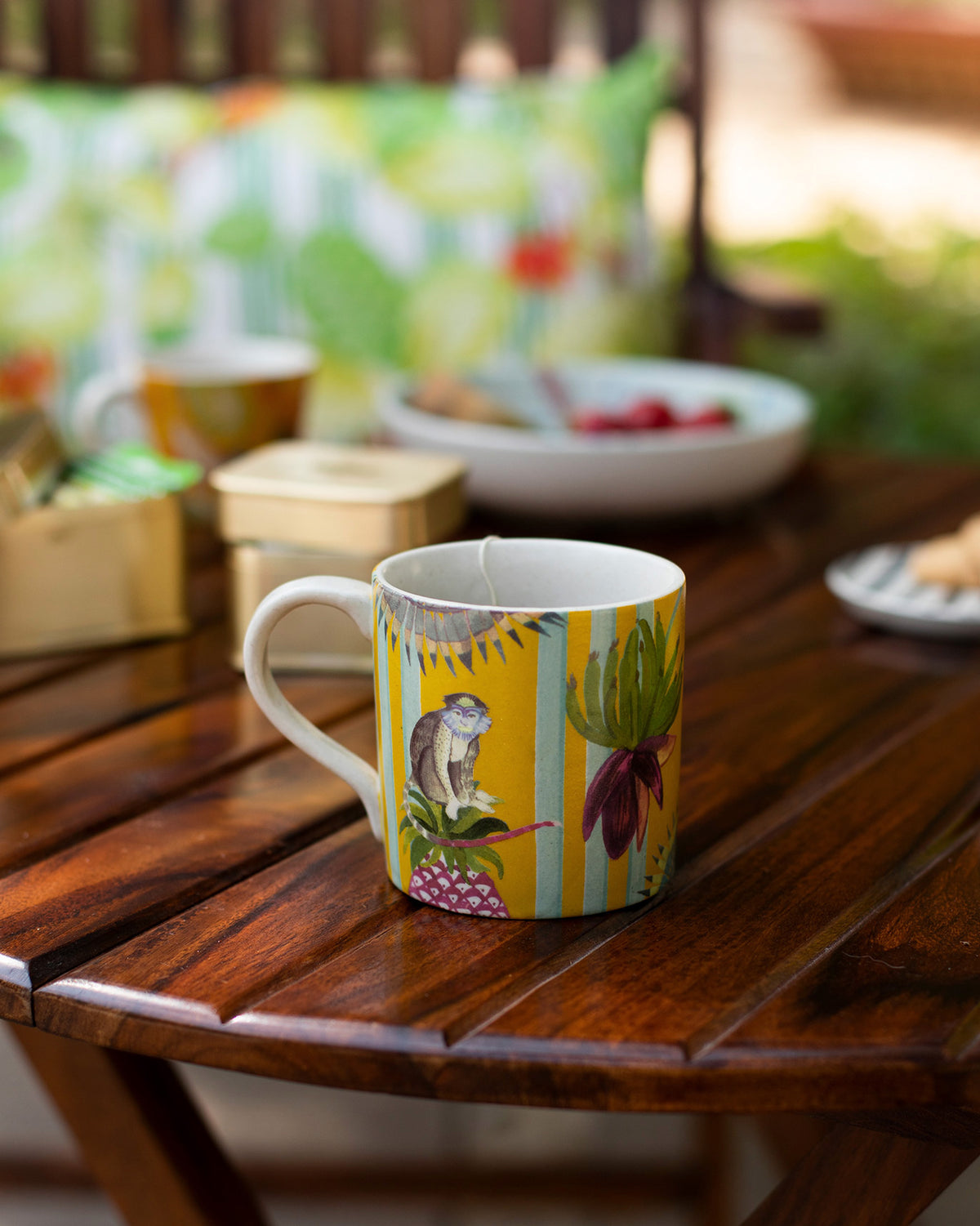 Side view of a yellow Mahi Mug with a monkey and leaf print.