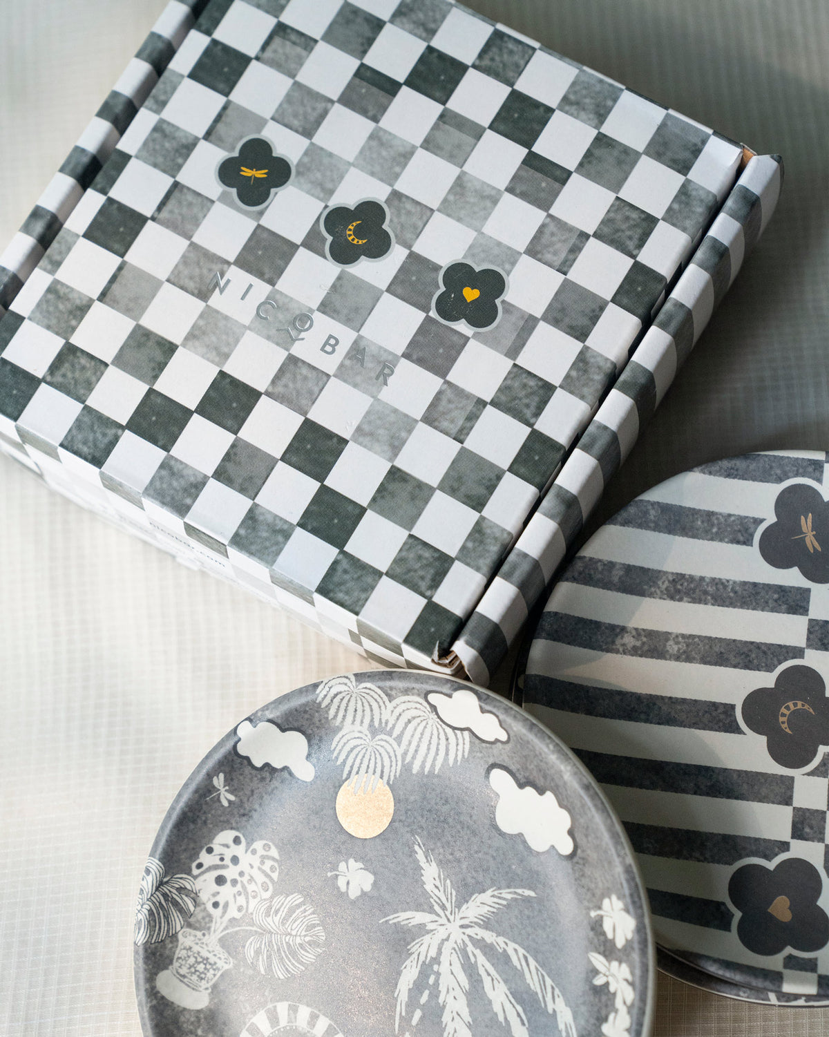 Nicobar box with a checkerboard pattern, shown beside Mandovi Tea Plates.