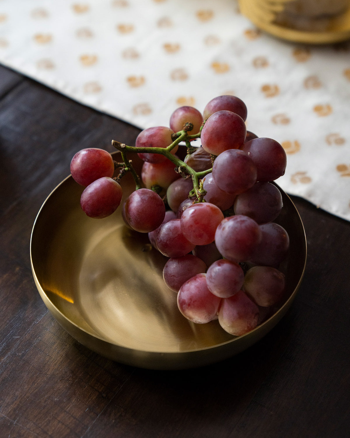 Brass Madhu shallow bowl filled with grapes.