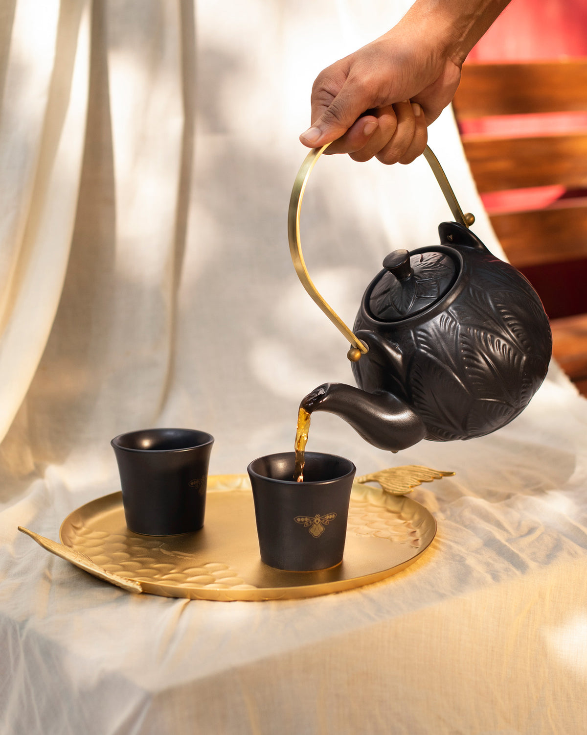 Black Moor teapot pouring tea into a matching cup.