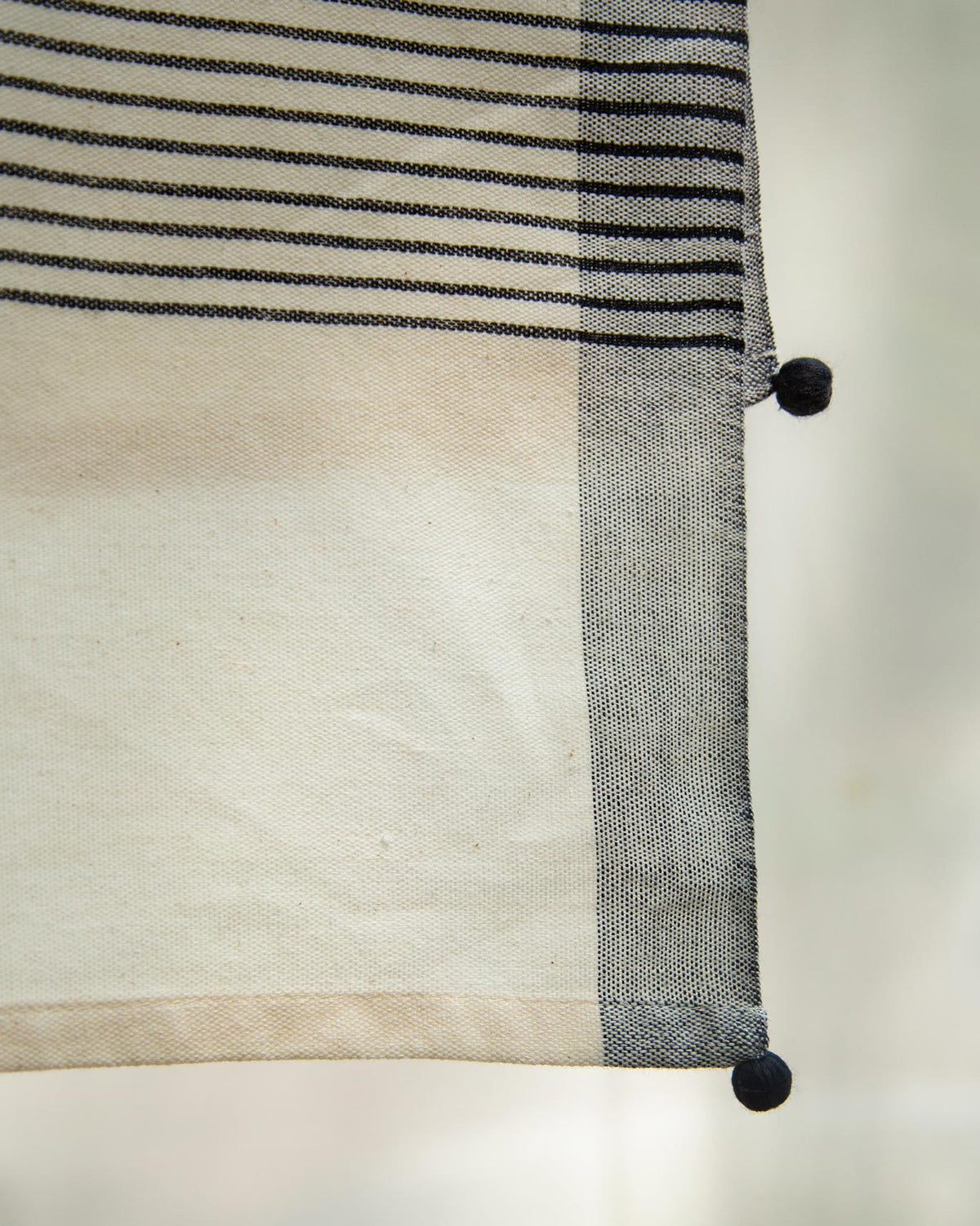 Close-up of Coast Towel corner showing its black stripes and pom-pom tassel.