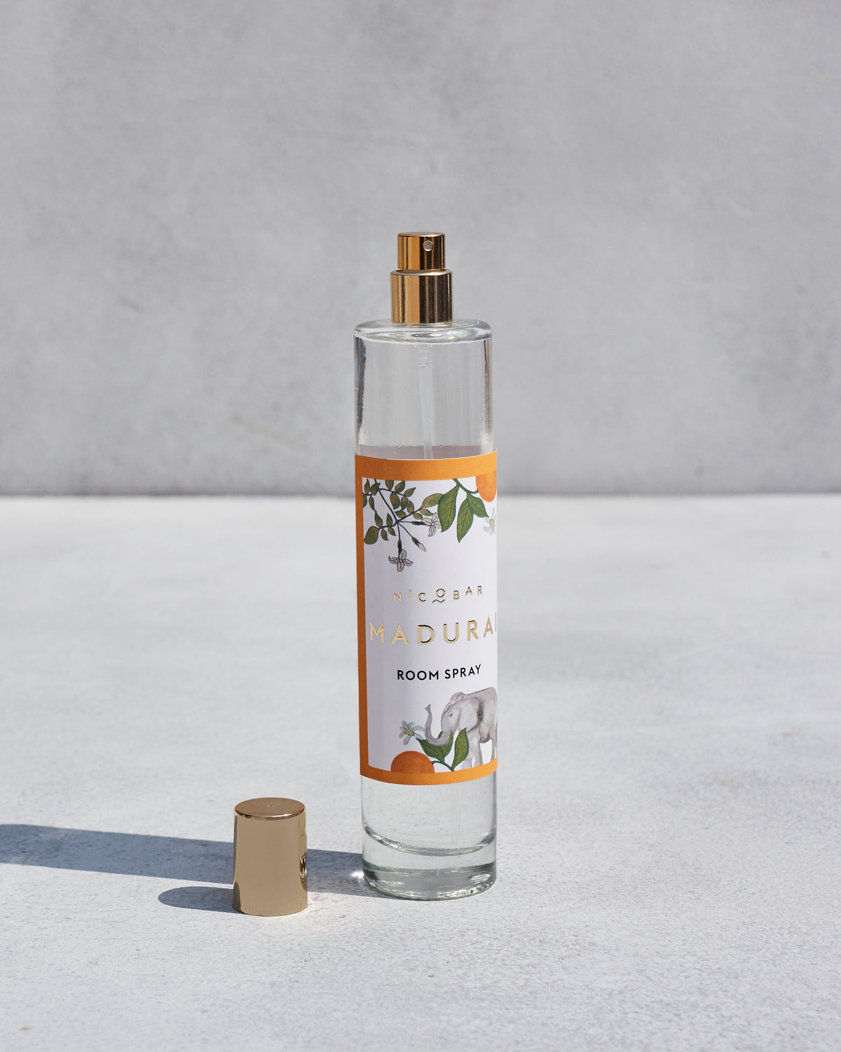 Madurai Room Spray with its gold cap set down beside the bottle.