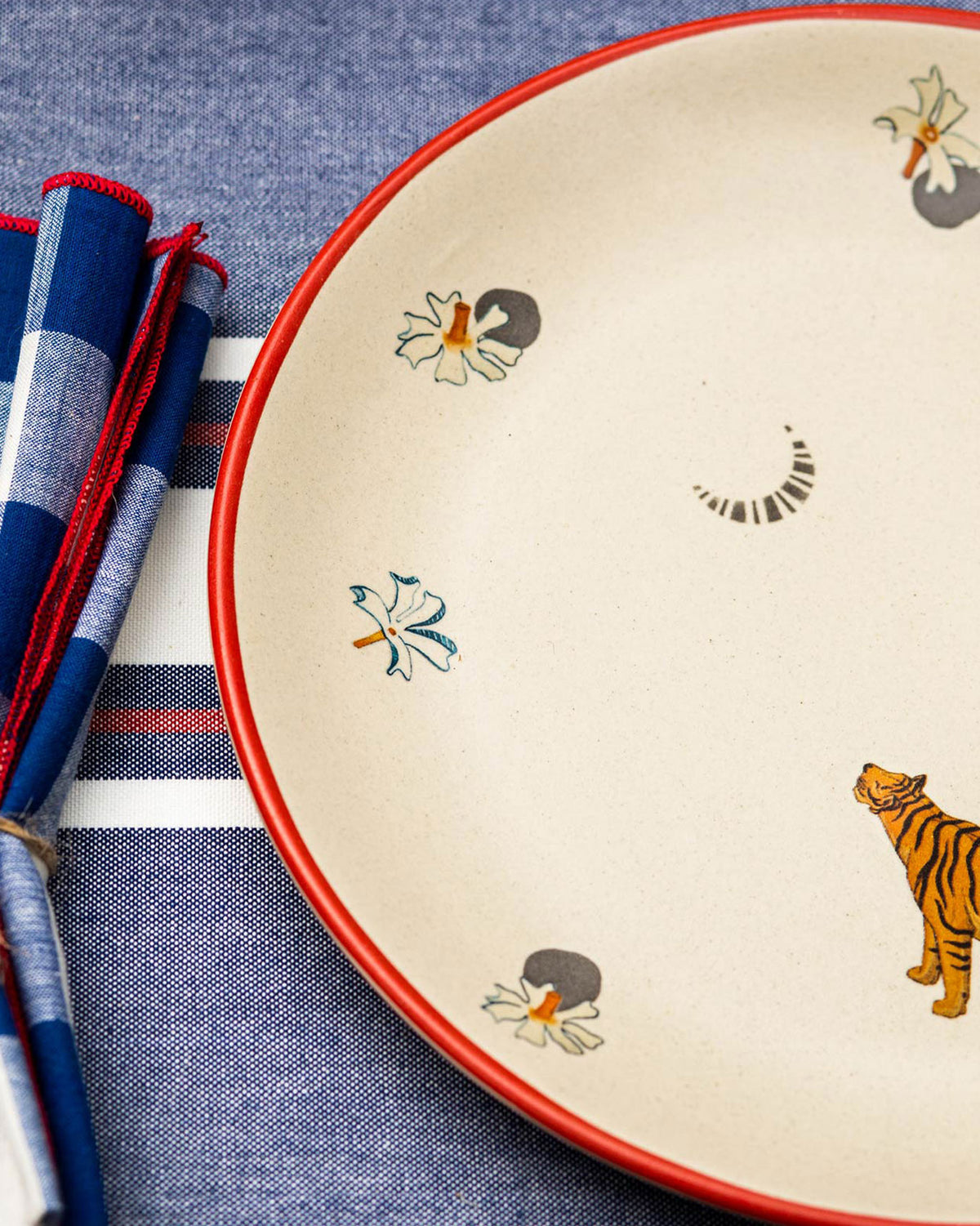 Close-up of Jheel Dinner Plate showing a tiger and small flower motifs inside a red rim.